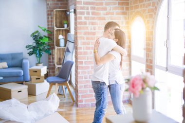 Karton kutular etrafında yeni evde sarılma genç güzel çift