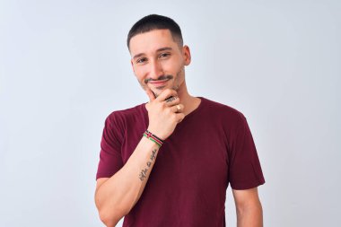 İzole edilmiş arka planda duran yakışıklı genç adam kameraya bakarak kollarını kavuşturup gülümseyerek çenesini kaldırdı. Olumlu düşünüyorum..
