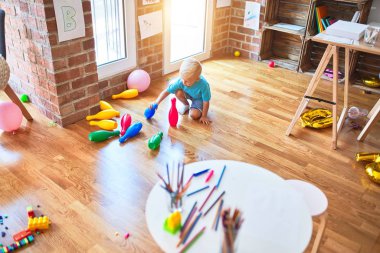Anaokulunda bowling oynayan beyaz bir çocuk. Anaokulu çocuğu oyuncaklarla oyun odasında mutlu.