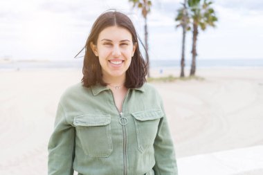 Genç güzel kadın plajda çok mutlu gülümseyen