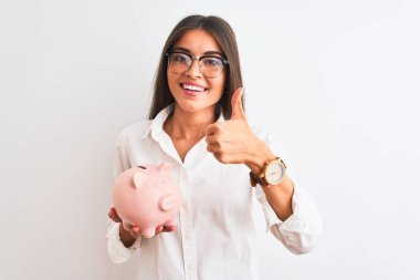 Gözlüklü güzel bir iş kadını, kumbarasını izole edilmiş beyaz arka planda tutuyor. Kocaman gülümsüyor ve gülümsüyor.