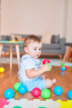 Anaokulunda küçük renkli toplarla oynayan güzel bir çocuk.
