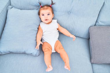 Anaokulunda kanepedeki renkli oyuncakların yanında mutlu bir bebek.