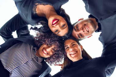 Bir grup iş adamı mutlu gülümsüyor. Kafa kafaya durmak, ofiste gülümseyerek sarılmak.