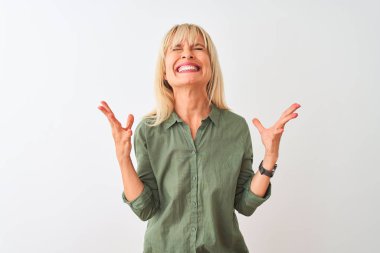 İzole edilmiş beyaz arka plan üzerinde duran yeşil tişörtlü orta yaşlı kadın kollarını kaldırmış ve gözleri kapalı heyecanla haykırarak başarının çılgınlığını kutluyor. Kazanan konsept