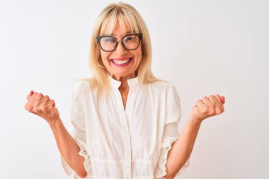 Orta yaşlı iş kadını gömlek ve gözlük takıyor, beyaz arka planda duruyor gururla bağırıyor, zaferi ve başarıyı kutluyor.