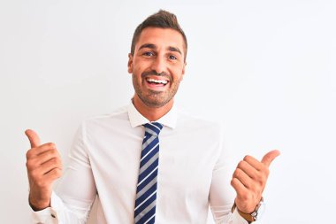 Genç yakışıklı, zarif iş adamı izole edilmiş arka plan başarı işareti el hareketleriyle olumlu jest yapıyor, gülümsüyor ve mutlu. Neşeli ifade ve kazanan jest.