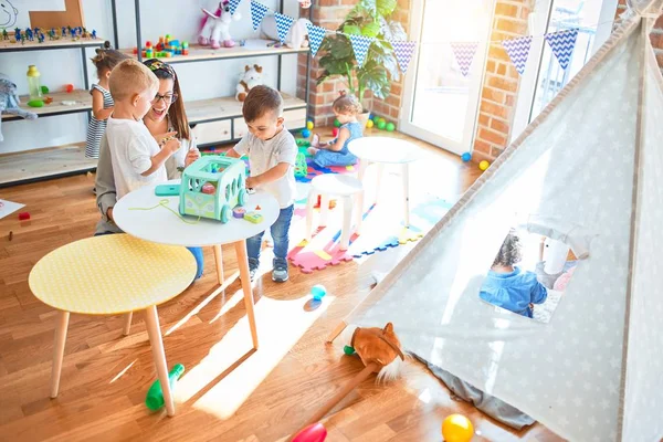 漂亮的老师和一群幼儿在幼儿园玩很多玩具 — 图库照片