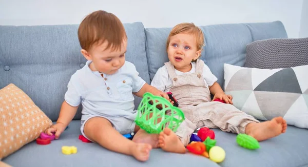 Belas Crianças Uma Delas Chorando Sentada Sofá Brincando Com Brinquedos — Fotografia de Stock