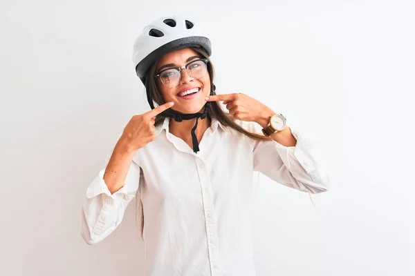 Beautiful businesswoman wearing glasses and bike helmet over isolated white background smiling cheerful showing and pointing with fingers teeth and mouth. Dental health concept.