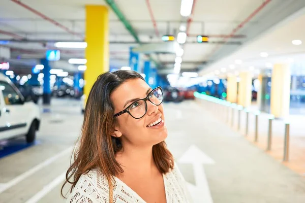車やライトの周りの地下駐車場で自信を笑顔若い女性 — ストック写真
