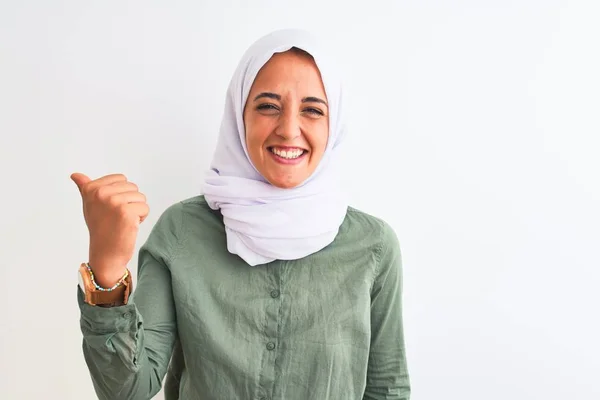 若いです美しいですアラブ女性身に着けています伝統的なイスラム教徒のヒジャーブ上の隔離された背景笑顔で幸せな顔を見て 親指アップで側面を指して — ストック写真