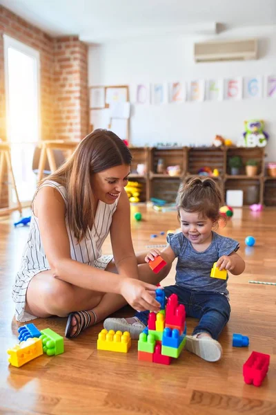 幼稚园的年轻漂亮老师和幼儿玩积木玩具 — 图库照片