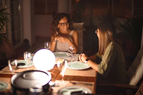 Beautiful mother and daughter on dinner smiling at terrace