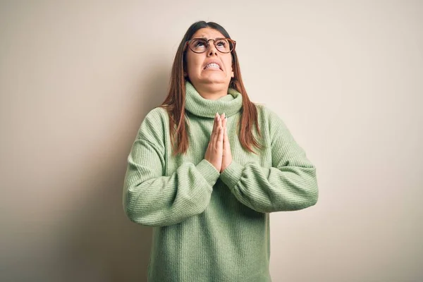 Young beautiful woman wearing casual sweater standing over isolated white background begging and praying with hands together with hope expression on face very emotional and worried. Begging.