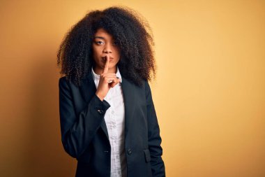 Afro saçlı, zarif ceketli, dudakları parmaklarıyla sessiz olmak isteyen güzel Afro-Amerikan iş kadını. Sessizlik ve gizli konsept.