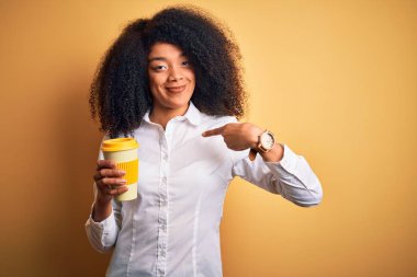 Afro saçlı, kahve içen, sürpriz yüzlü, kendini gösteren Afro Amerikalı genç bir iş kadını.