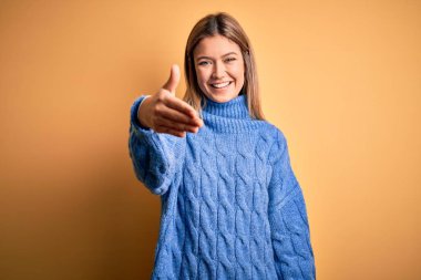 Sarıya boyanmış sarı arka plan üzerine balıkçı yaka kazak giyen genç, güzel sarışın bir kadın selamlama ve hoş geldin hediyesi olarak gülümseyerek el sıkışır. Başarılı bir iş..