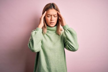 Pembe yünlü arka plan üzerine kışlık yün kazak giyen genç, güzel sarışın bir kadın. Stres yüzünden baş üstü baş ağrısı çekiyor. Migren ağrısı..