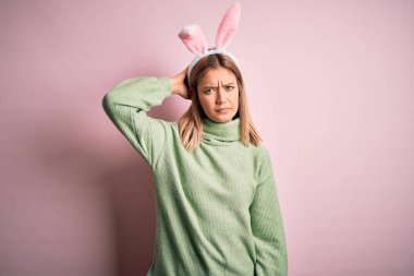 Paskalya tavşanı kulakları takan genç ve güzel bir kadın soyutlanmış pembe arka planda duruyor. Soruyu merak ediyor. Şüpheyle kararsız, kafa kafaya düşünerek. Düşünceli kavram.