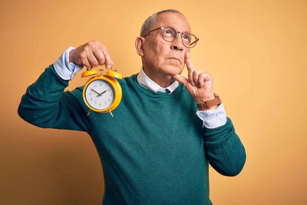 Senior Handsome Man Holding Alarm Clock Standing Isolated Yellow Background — ストック写真