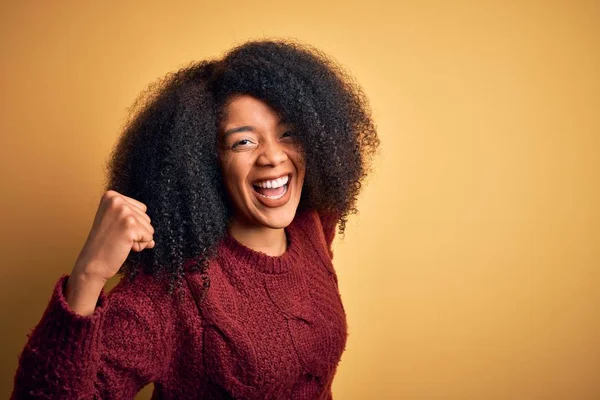 黄色の隔離された背景の上に立ってアフロの髪を持つ若い美しいアフリカ系アメリカ人女性は 腕を上げて開いて目で成功したことに驚きと驚きを祝います 勝者のコンセプト — ストック写真