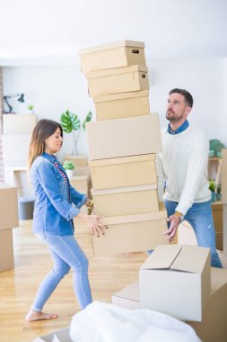 Genç güzel çift yeni evde karton kutu yığını tutan