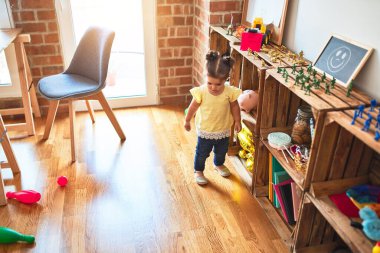 Anaokulunda bir sürü oyuncağın etrafında duran güzel çocuk.
