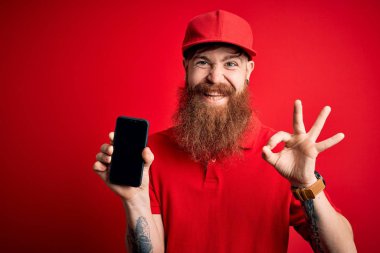 Kızıl saçlı, sakallı, akıllı telefonlu İrlandalı teslimatçı ekranda uygulama gösteriyor. Parmaklarıyla tamam işareti yapıyor. Mükemmel bir sembol.