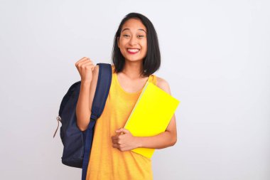 Sırt çantasıyla gezen Çinli genç bir bayan izole edilmiş beyaz arka plan üzerine kitap tutuyor gururla bağırıyor ve zaferi ve başarıyı kutluyor çok heyecanlı, coşkulu bir duygu.