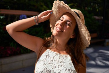 Güneşli bir yaz gününde yeşil parkta mutlu ve neşeli gülümseyen güzel bir kadın.