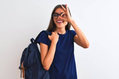 Young beautiful student woman wearing backpack and glasses over isolated white background with happy face smiling doing ok sign with hand on eye looking through fingers
