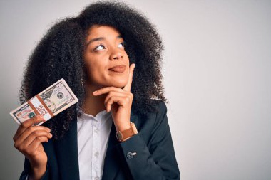 Afro saçlı Afrikalı Amerikalı genç bir iş kadını elinde bir sürü nakit para tutuyor. Yüzü ciddi ciddi soruyla dolu, kafası karışık bir fikir.