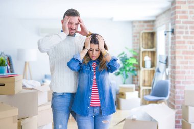 Genç ve güzel bir çift yeni evlerinde karton kutuların etrafında dikilip acı ve migren yüzünden çaresiz ve stresli bir şekilde acı çekiyorlar. Ellerini başının üstüne koy..