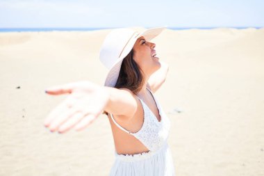 Kollarını açmış güneşlenen genç ve güzel bir kadın yaz tatilinin tadını çıkarıyor.