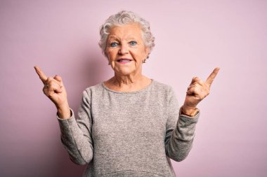 Senior beautiful woman wearing casual t-shirt standing over isolated pink background smiling confident pointing with fingers to different directions. Copy space for advertisement