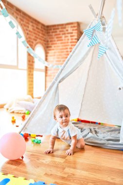 Anaokulunda bir sürü oyuncakla oynayan sevimli bir çocuk.