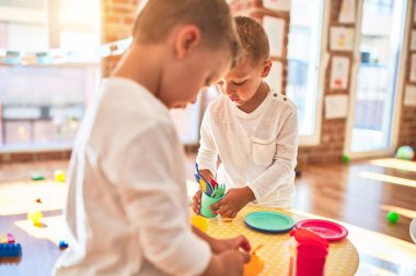 Adorable blonde twins playing around lots of toys. Cooking plastic food toy at kindergarten