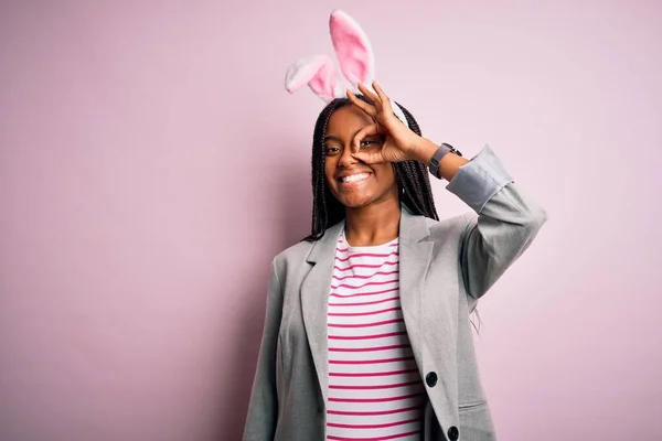年轻的非洲裔美国女孩 头戴可爱的复活节兔子耳朵 背景粉红 手握微笑 眼睛看着手指 面带笑容 — 图库照片