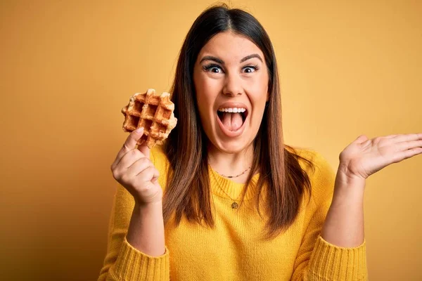 Joven Hermosa Mujer Comiendo Pastelería Dulce Waffle Sobre Fondo Amarillo — Foto de Stock