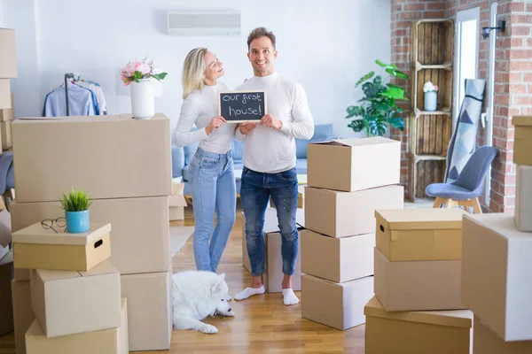 Karton kutuların etrafındaki yeni evlerinde ellerinde karatahtayla bekleyen genç ve güzel bir çift.