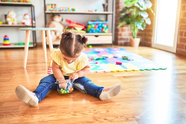美しい幼児は幼稚園でチョコレート色のボールの瓶で床に座っています — ストック写真