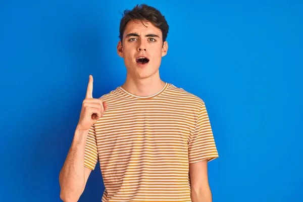Teenager Junge Lässigem Shirt Vor Blauem Hintergrund Mit Erhobenem Zeigefinger — Stockfoto