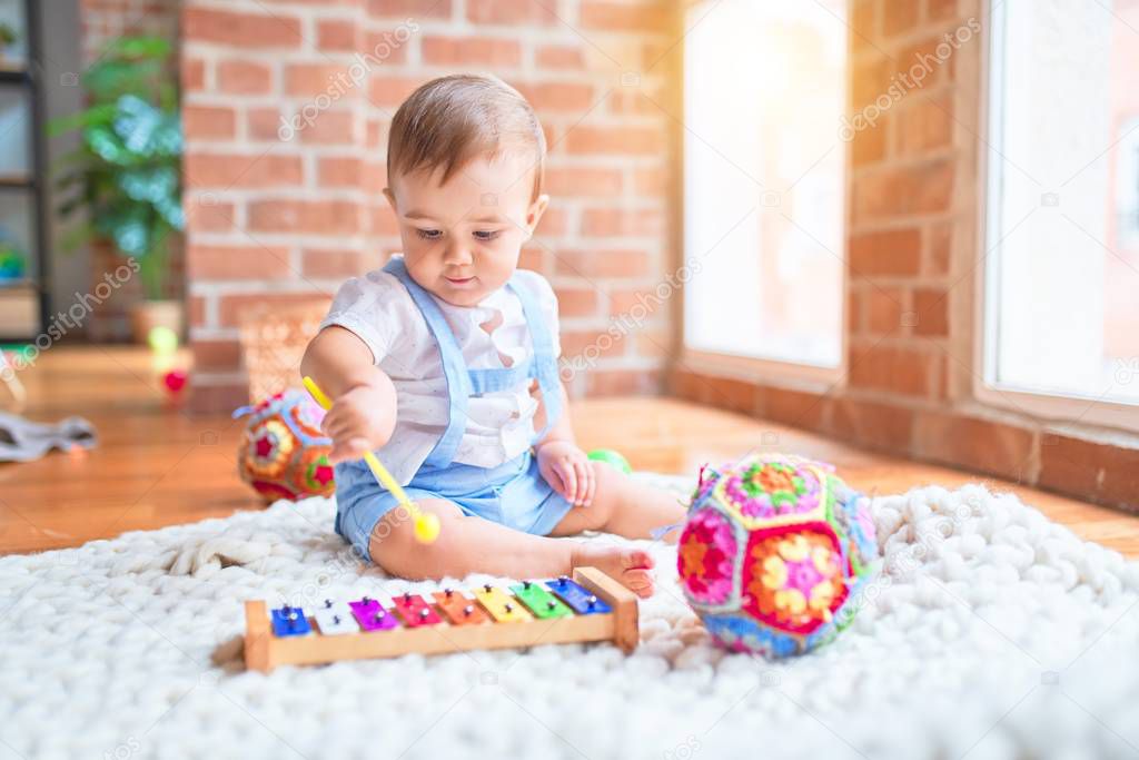 Beautiful toddler sitting on the blanket playing xylophone smiling at kindergarten