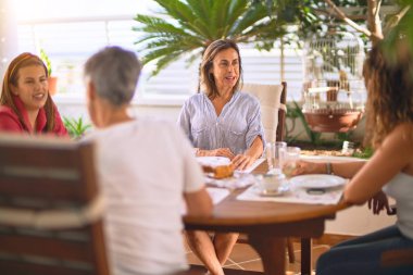 Genç ve güzel bir kız mutlu ve kendinden emin bir şekilde terasta oturmuş bir fincan kahve içiyor.
