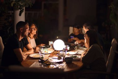 Güzel bir aile akşam yemeğinde terasta konuşuyor ve gülümsüyor