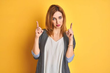 Redhead caucasian business woman over yellow isolated background shaking and freezing for winter cold with sad and shock expression on face