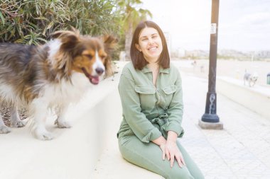 Genç ve güzel bir kadın köpeğiyle bankta oturuyor.