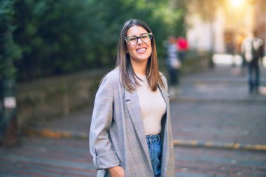 Mutlu ve kendinden emin gülümseyen genç ve güzel bir kadın. Kasaba caddesinde yüzünde gülümsemeyle dikilirken