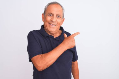 Senior grey-haired man wearing black casual polo standing over isolated white background cheerful with a smile of face pointing with hand and finger up to the side with happy and natural expression on face